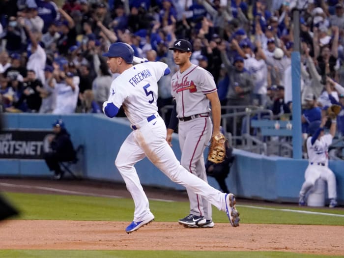 Los Angeles Dodgers’ Freddie Freeman, left, rounds first after hitting a solo home run as Atlanta Braves first baseman Matt Olson watches during the first inning of a baseball game Monday, April 18, 2022, in Los Angeles.